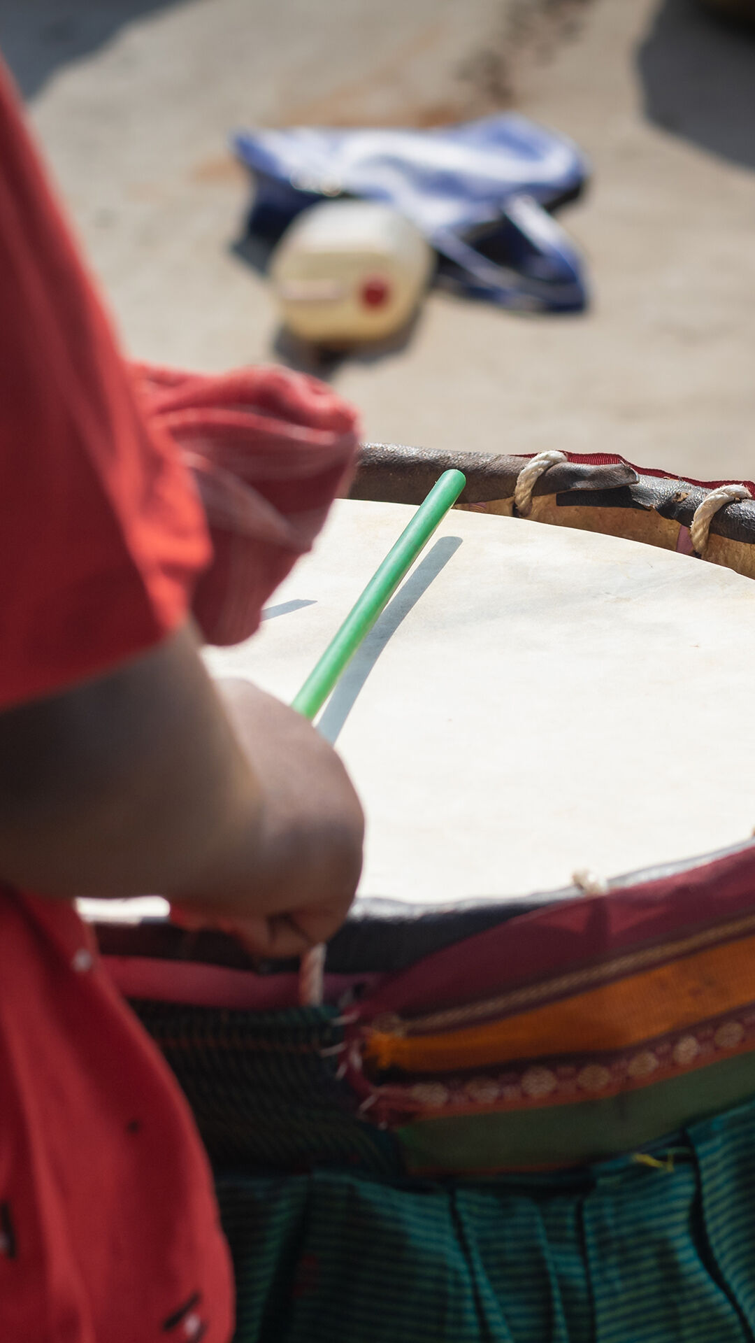 Hand beating a traditional Bengali drum with sticks, symbolizing the vibrant musical traditions of Bengali weddings